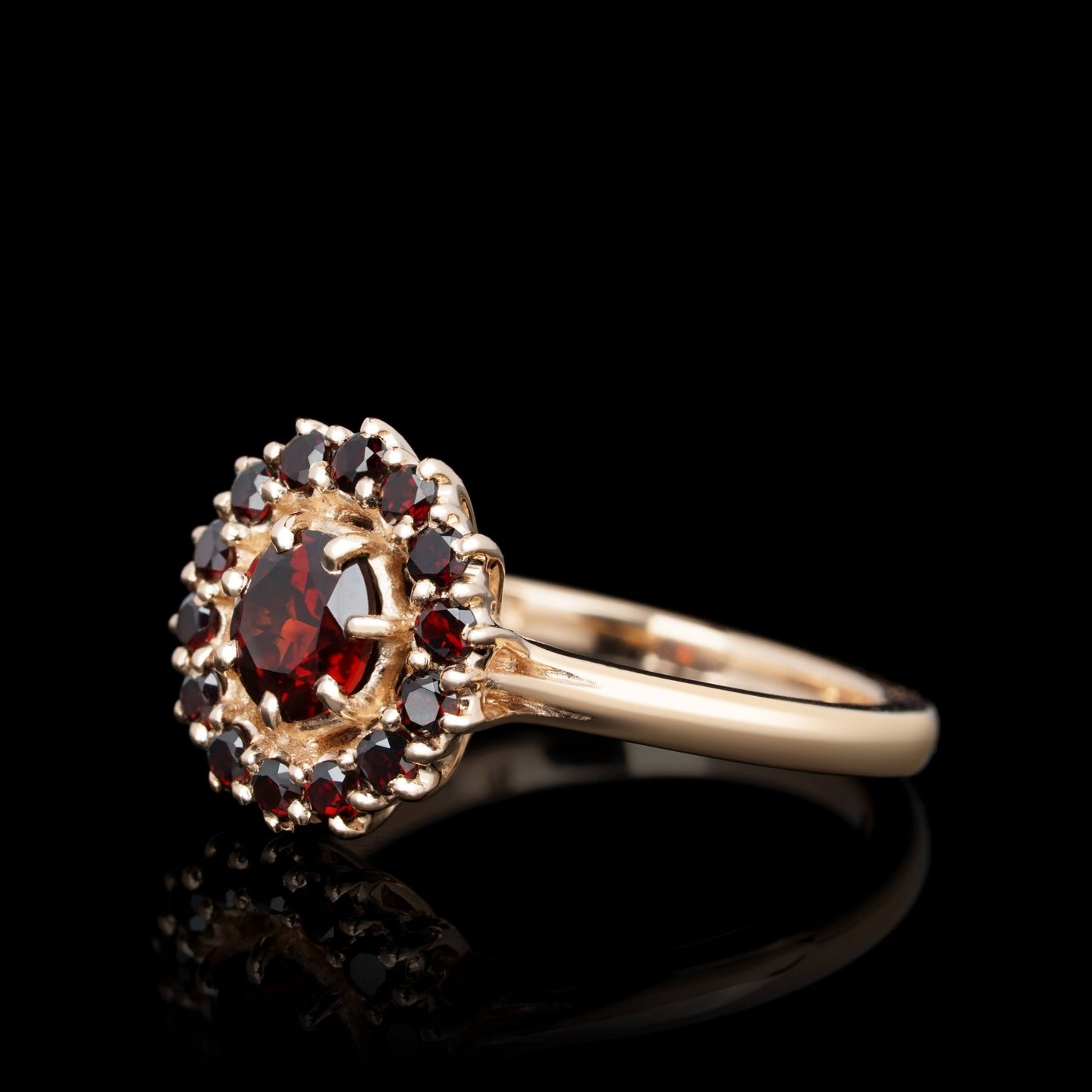 Fiery Allure ring in red 14K gold with garnet centerpiece and accent stones on a black background.