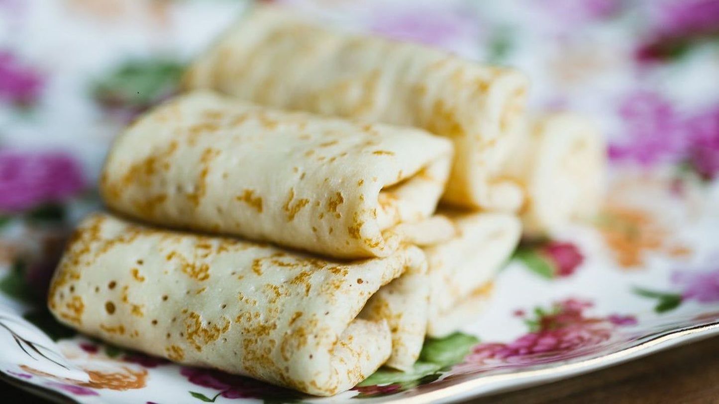 Homemade Ukrainian crepes filled with savory ingredients on a floral plate, thin, delicate, and frozen, perfect for any meal.