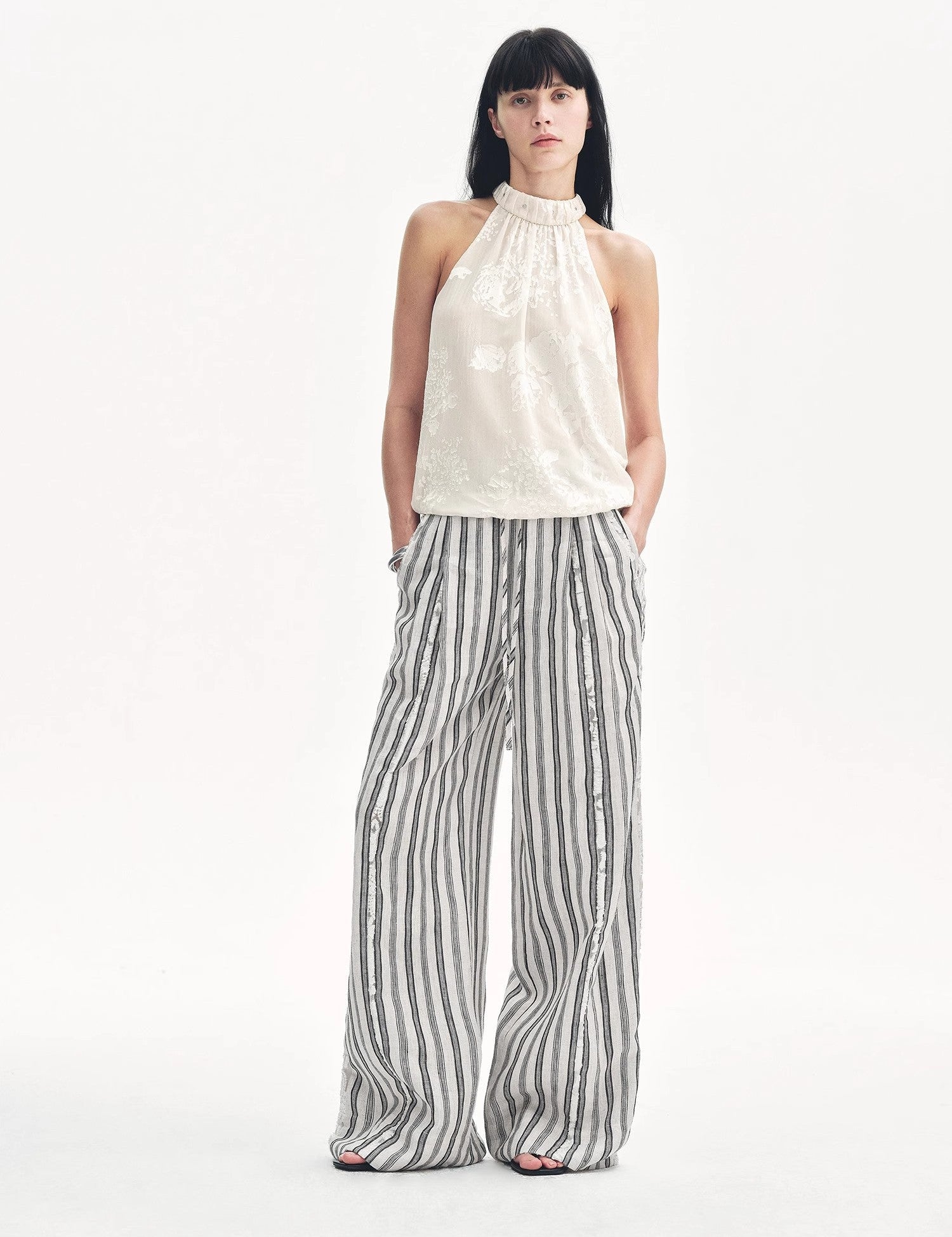 Woman wearing Elireth Burnt-Floral Halter top with striped wide-leg pants, showcasing elegant fashion style.