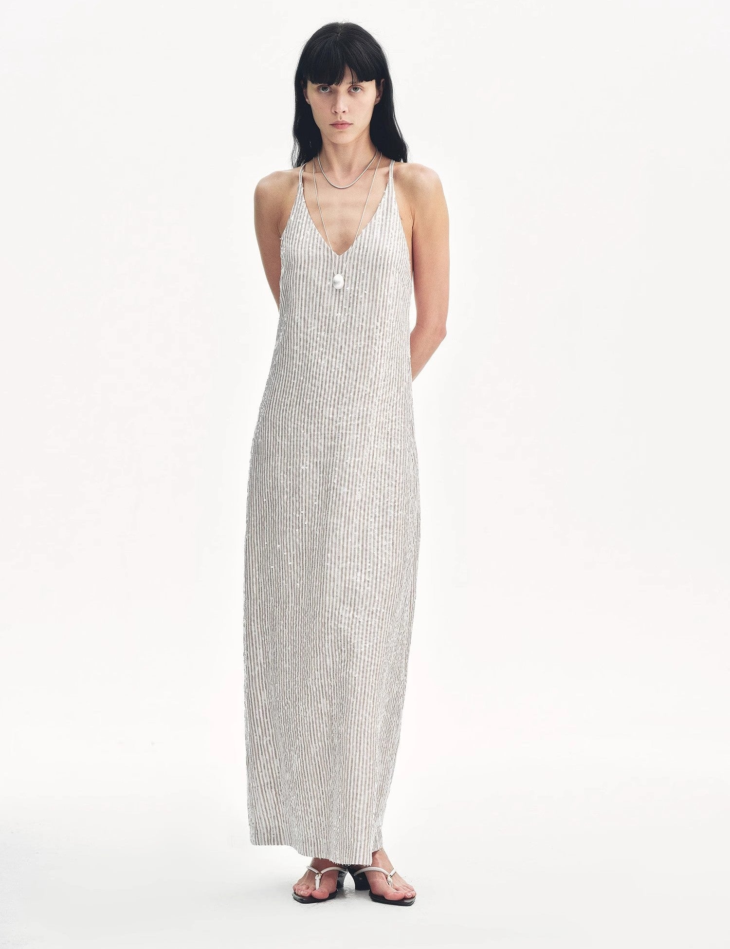 Woman wearing Astrenya Sequin Linen Maxi Dress with V-neckline, thin straps, and open back detail, showcasing shimmering sequin embroidery.