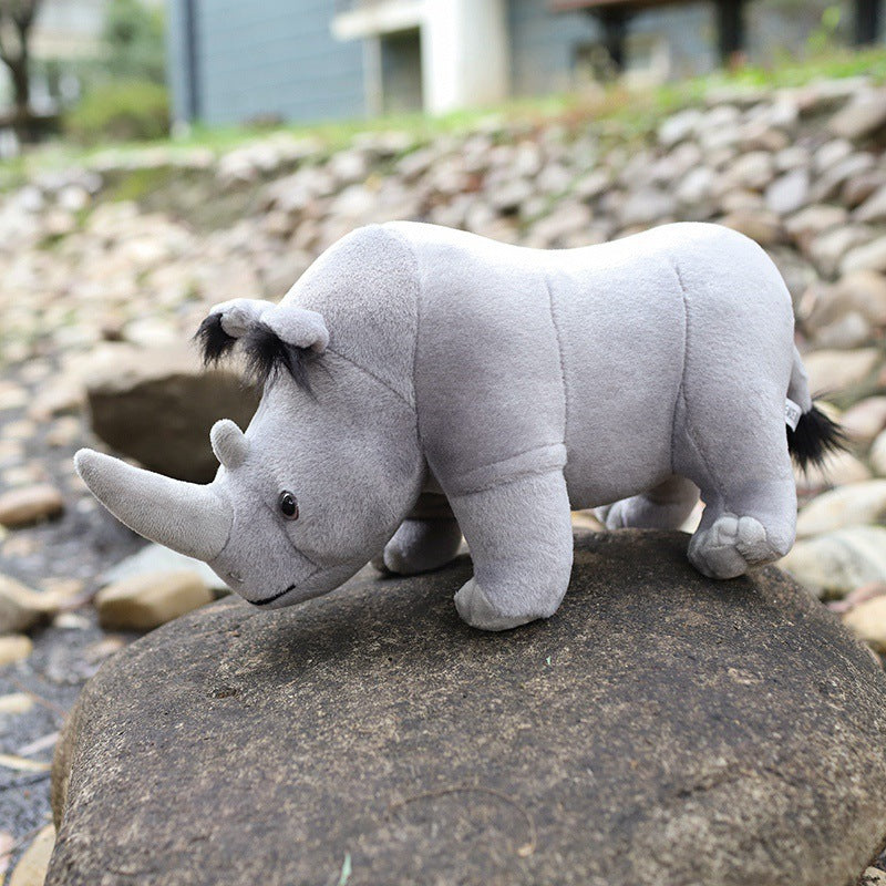 Cute rhino plush toy on a rock outdoors, soft and huggable stuffed animal, perfect gift for teenagers, made with PP cotton filling.