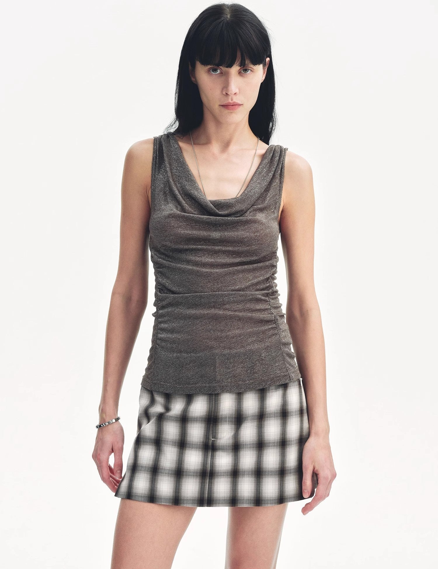 Model wearing Zirellin Drape Contour Vest with draped neckline and plaid skirt, showcasing a modern, feminine style.