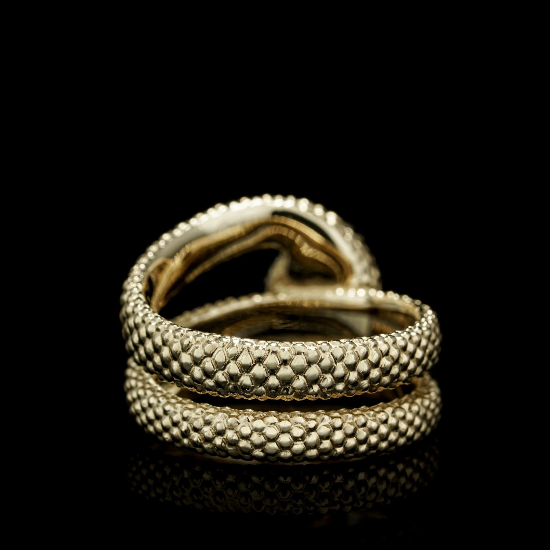 Yellow gold serpent motif ring with intricate texture on a black background.