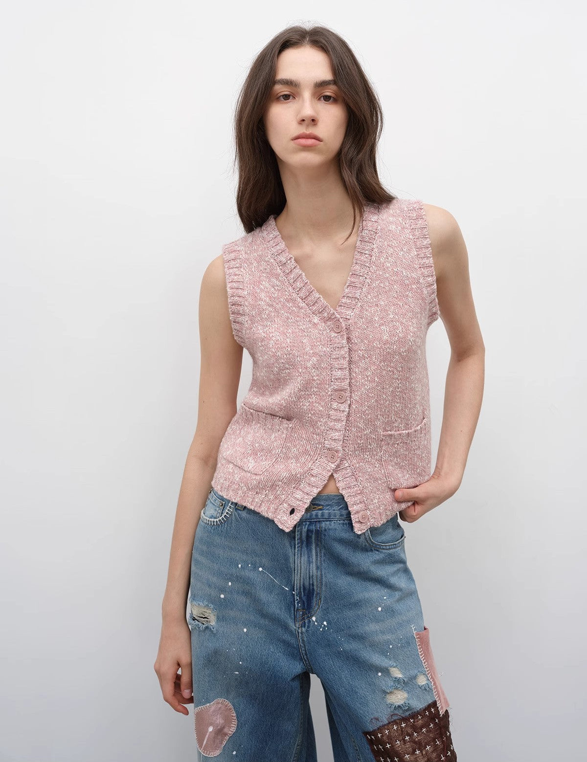 Woman wearing a pink Ferwynn Dotted Merino Vest with a V-neck and textured color-block design, styled for urban elegance and warmth.