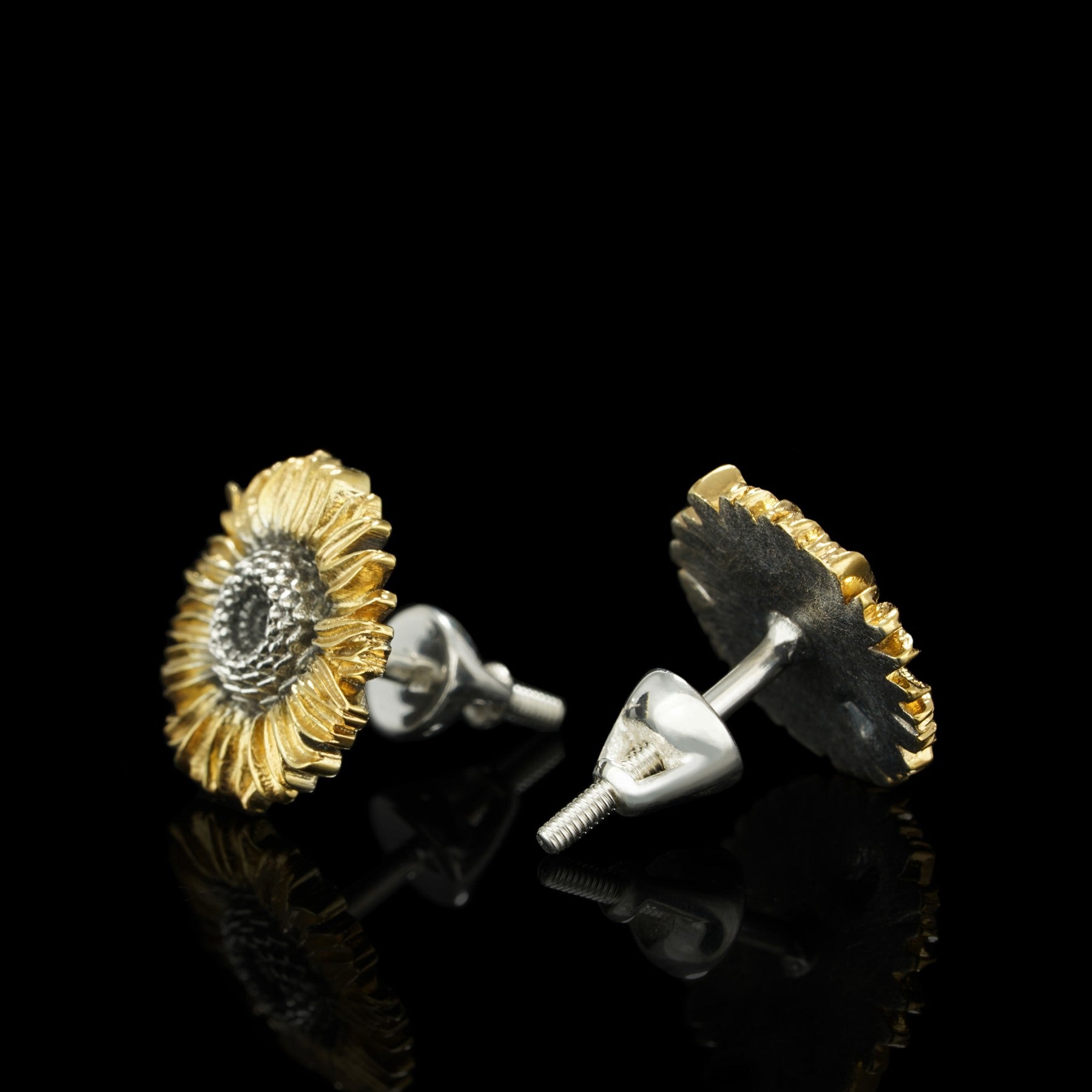 Sterling silver sunflower earrings with gilded petals, featuring exquisite oxidation details, displayed on a black reflective surface.