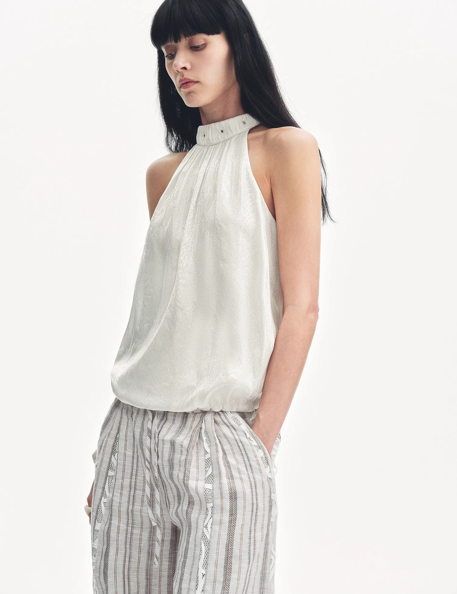 Woman wearing Elireth Burnt-Floral Halter with pleated A-line hem, showcasing elegant design and gentle floral texture in a studio setting.