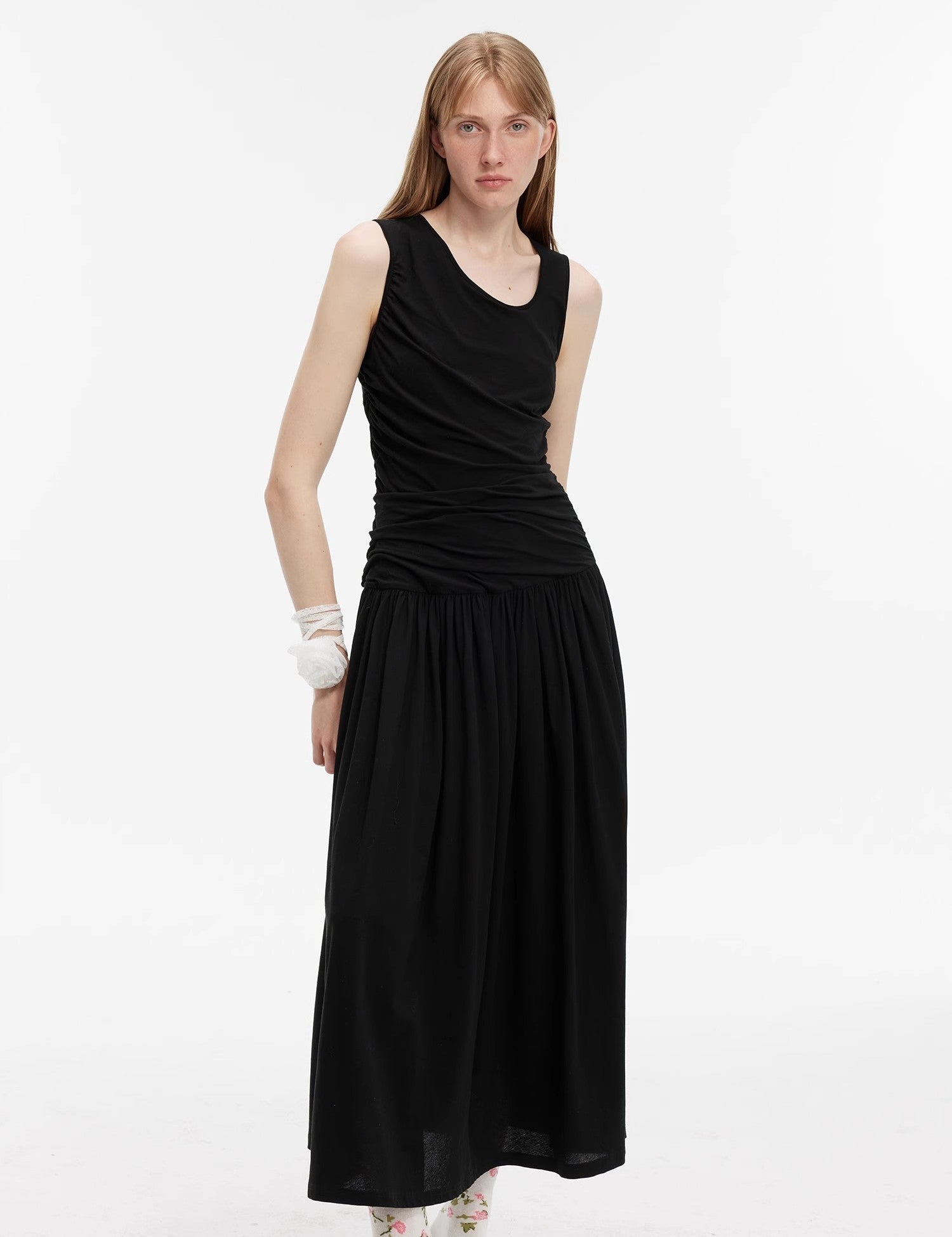 Woman wearing a black Calvara Pleated Cotton Maxi Dress with an asymmetrical collar and angled pleats, showcasing a relaxed, elegant style.