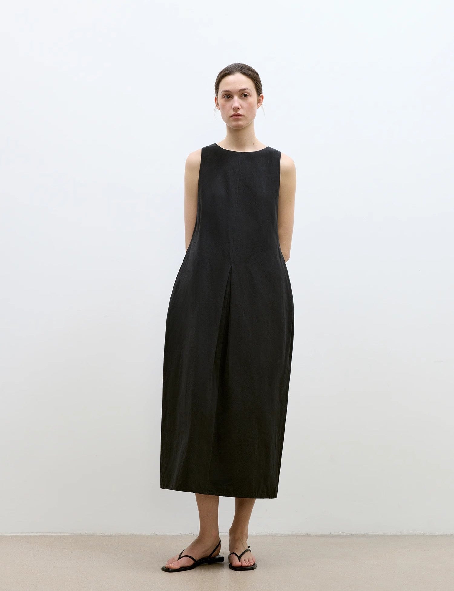 Woman wearing black Serelis Cotton-Linen Hourglass Dress with tailored waist and pleats, pairing elegance with comfort and style.