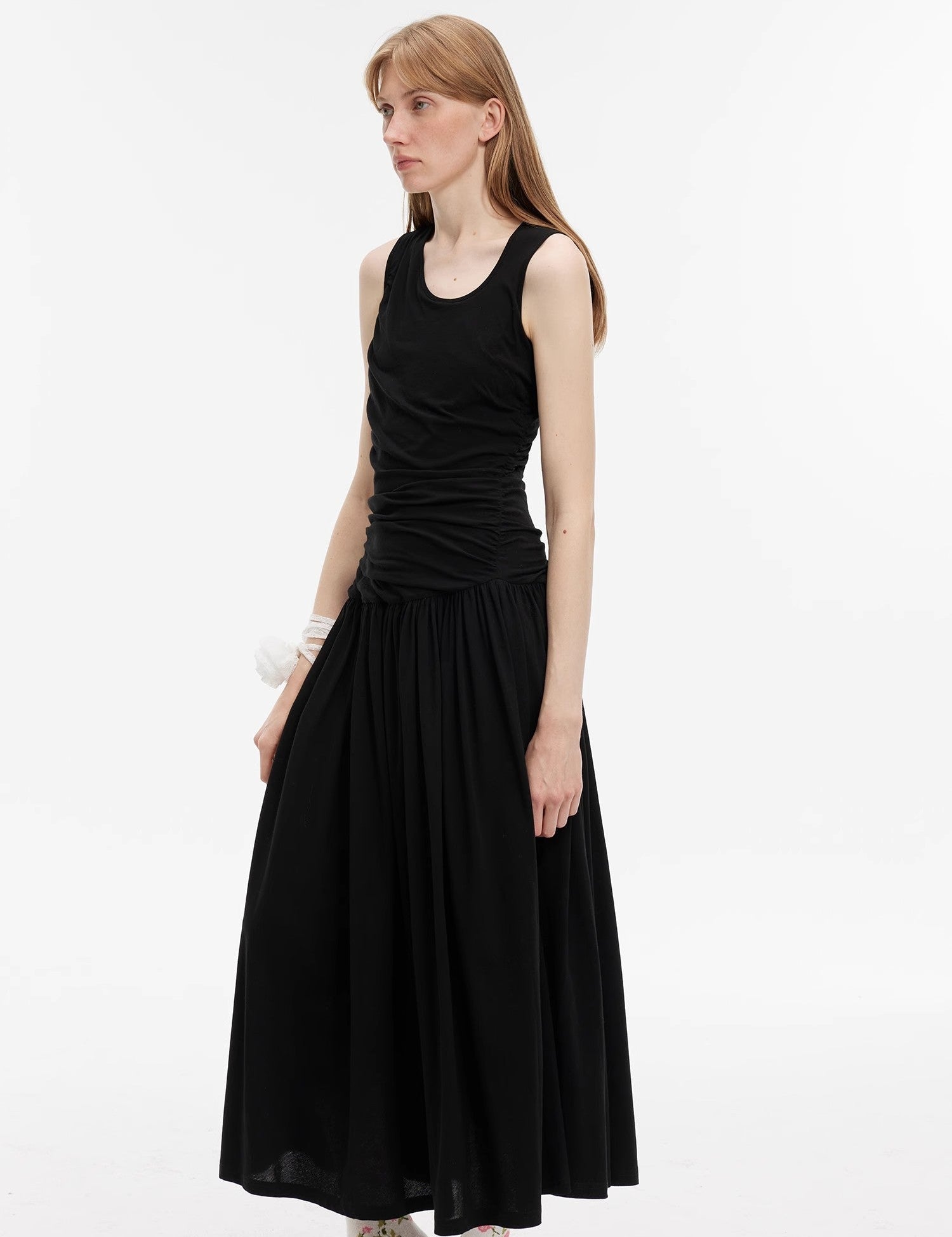 Model wearing Calvara Pleated Cotton Maxi Dress in classic black, featuring sleeveless design and asymmetrical pleats for elegant comfort.