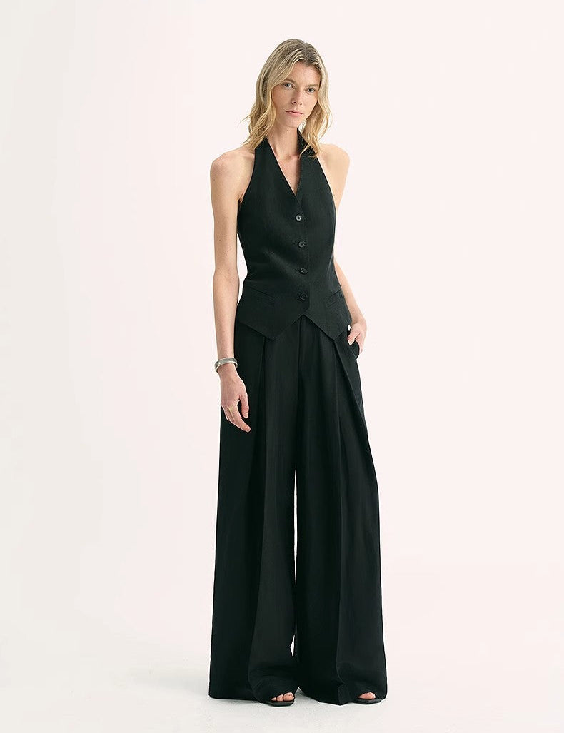 Woman wearing Solianne Silklinen Halter vest in black, featuring a V neckline and tailored cut, paired with wide-leg trousers.