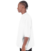 Side view of a model wearing a white oversized drop-shoulder crewneck t-shirt by Shaka Wear, showcasing its relaxed streetwear fit.