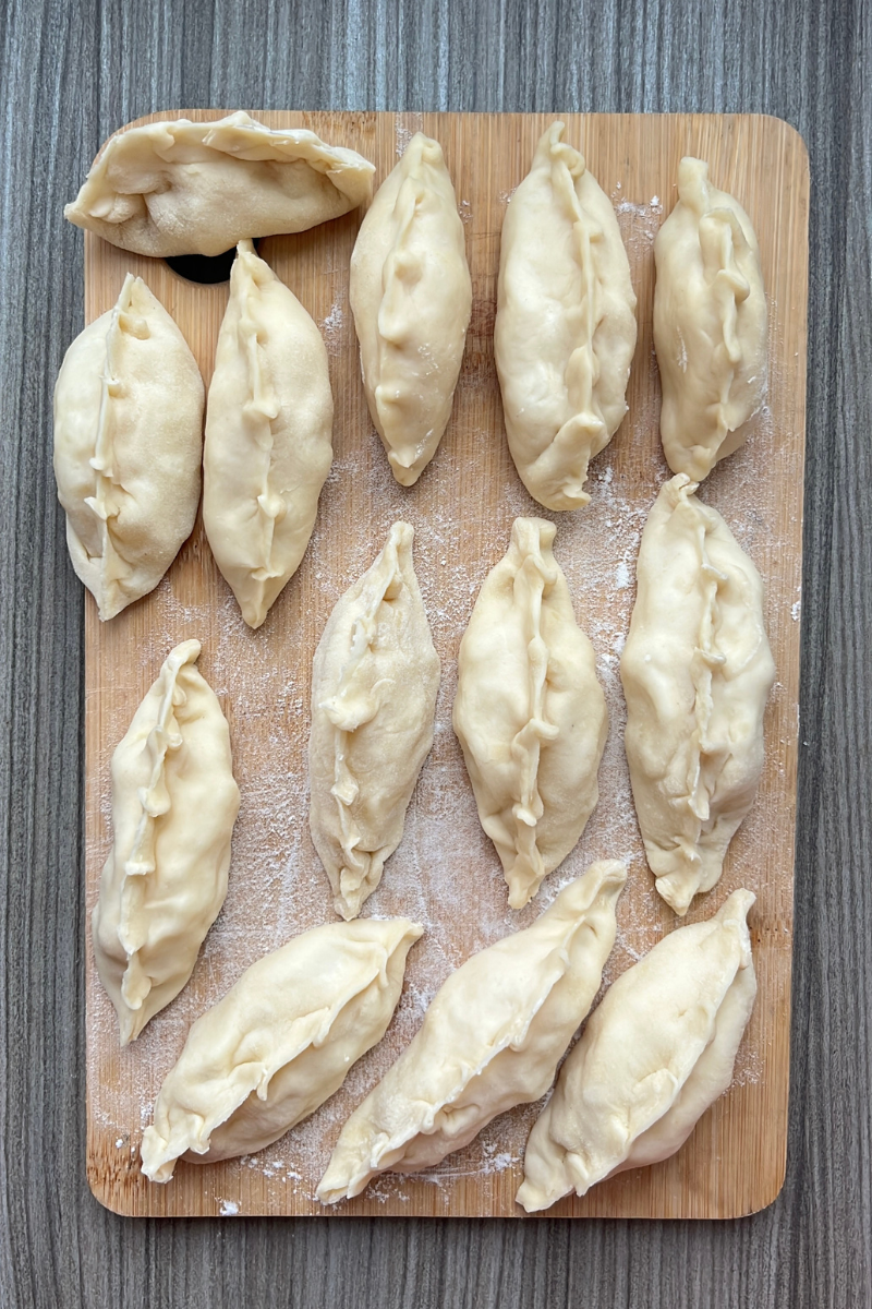 Homemade Ukrainian varenyky dumplings on a wooden board, showcasing traditional fillings of potato, cabbage, or farmer’s cheese.