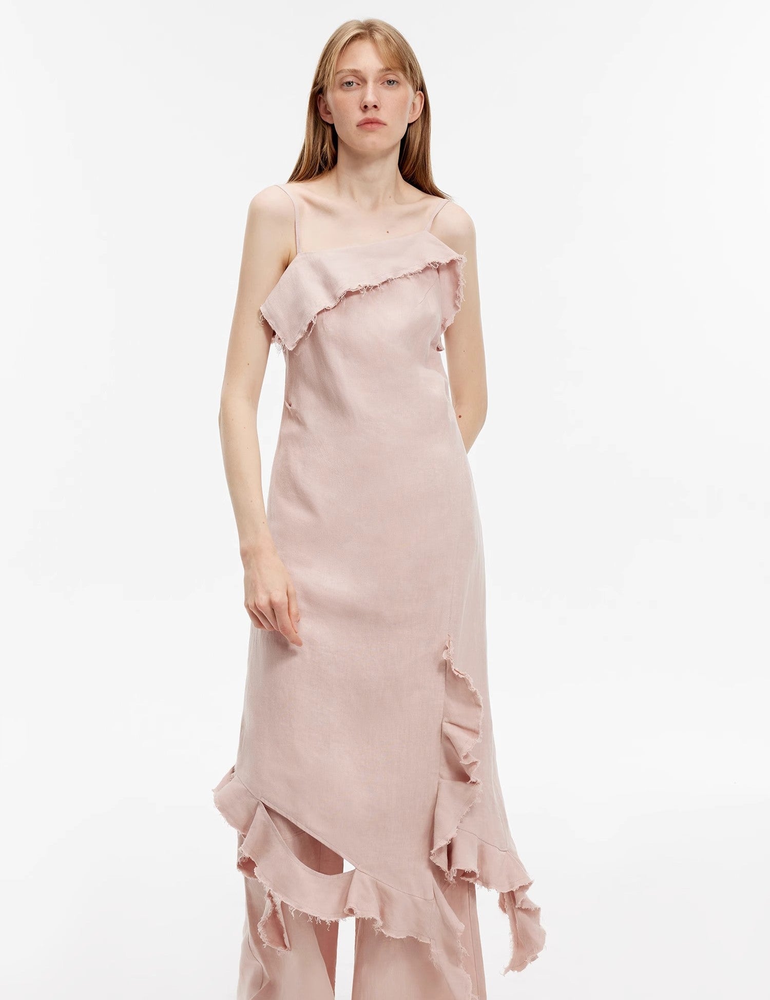 Woman wearing Elanys sand-washed linen ruffle dress with asymmetric neckline and flowing silhouette, highlighting summer romance.