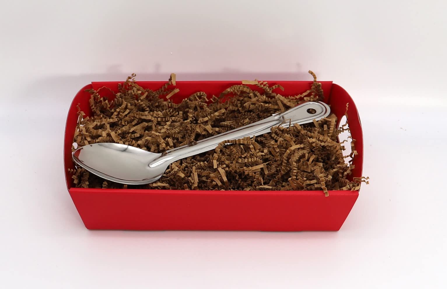 Stainless steel spoon in a red gift box with brown crinkle paper filling.