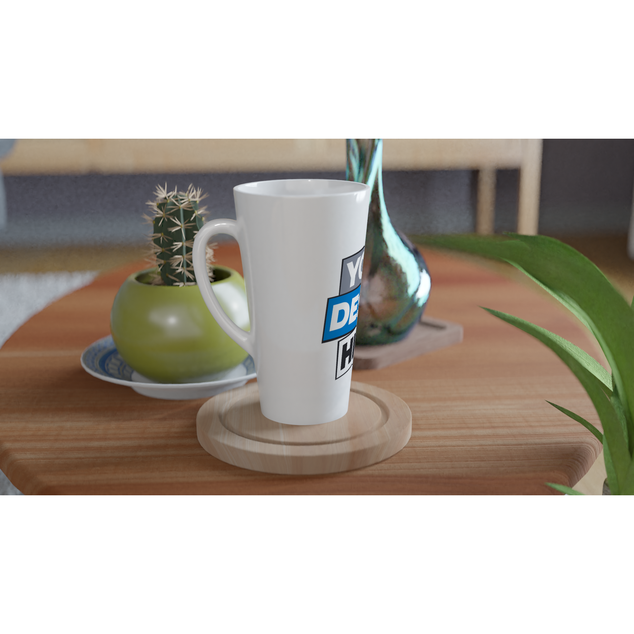 White 17oz ceramic latte mug with custom print design on wooden table, perfect for coffee or warm beverages, next to a plant and vase.