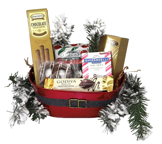 Holiday gift basket with chocolates, rolled wafers, festive treats, and evergreen decor, perfect for Christmas celebrations.