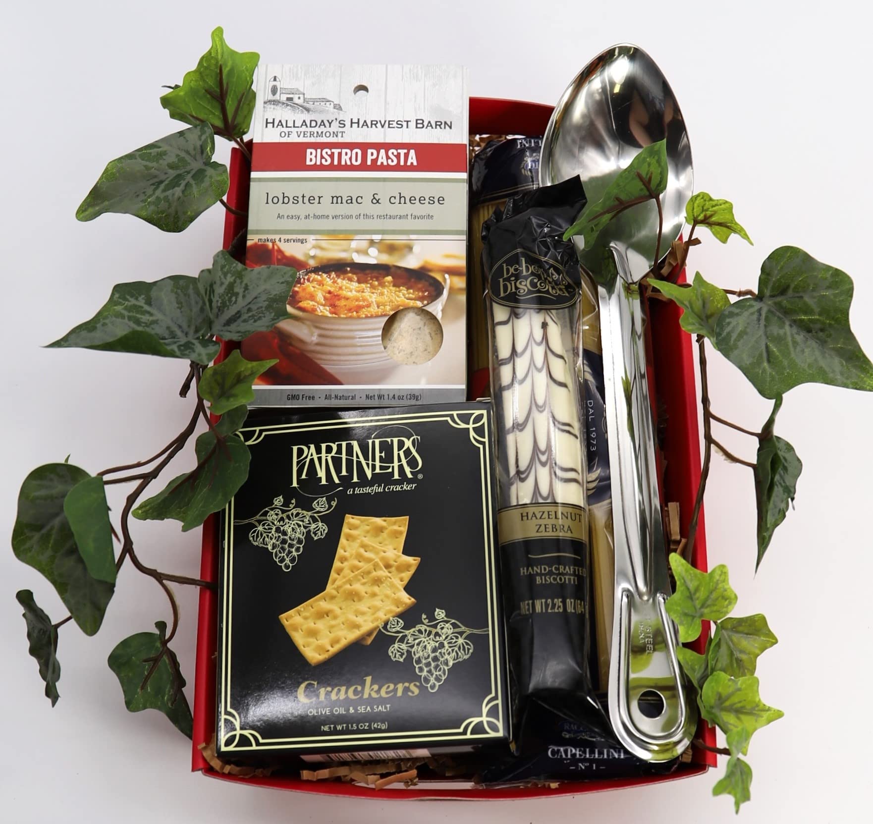 Italian gourmet gift tray with pasta, biscotti, crackers, and utensils adorned with fresh ivy.