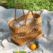 Handmade rattan-like picnic basket on plaid blanket with oranges, stylish and portable for outings or home decor.