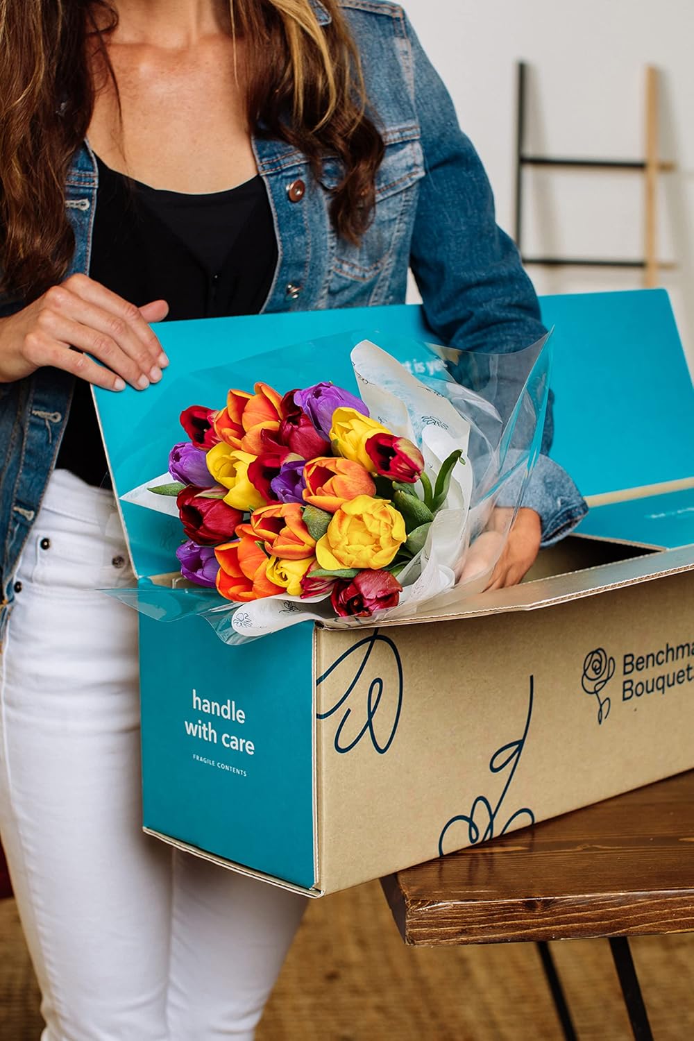 Woman unboxing 20-stem rainbow tulip bouquet with vibrant flowers in a blue box.