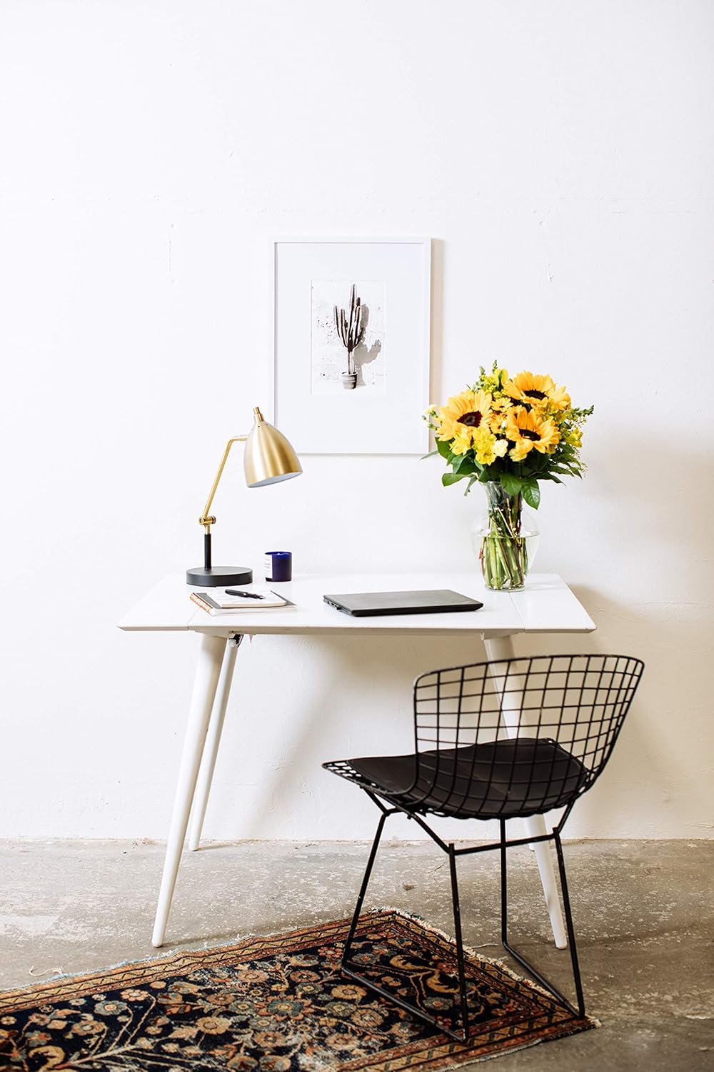 Modern workspace with black chair and desk featuring Rays of Sunshine bouquet with sunflowers in a glass vase.