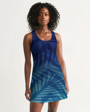 Woman wearing Sunset Hour Racerback Dress with blue leaf design, featuring a sleeveless cut and scoop neckline for a relaxed, breezy look.