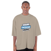 Model wearing men's oversized drop-shoulder crewneck t-shirt in beige, featuring "Your Design Here" text.