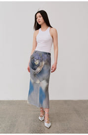 Woman wearing a slim white cotton camisole paired with a floral printed midi skirt and strappy heels, standing against a plain background.