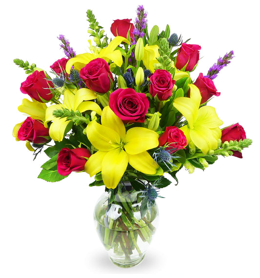 Joyful Wishes Bouquet with pink roses, yellow lilies, snapdragons, thistle, and purple liatris in a glass vase.