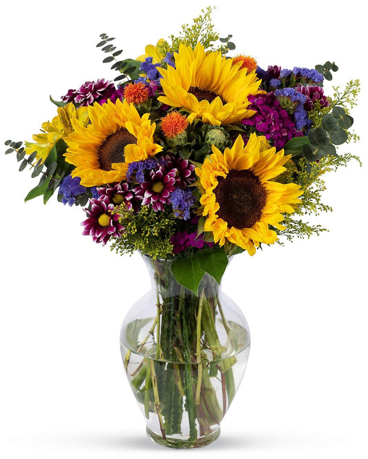 Vibrant Flowering Fields Bouquet with sunflowers and seasonal blooms in a glass vase, perfect for celebrations and brightening spaces.