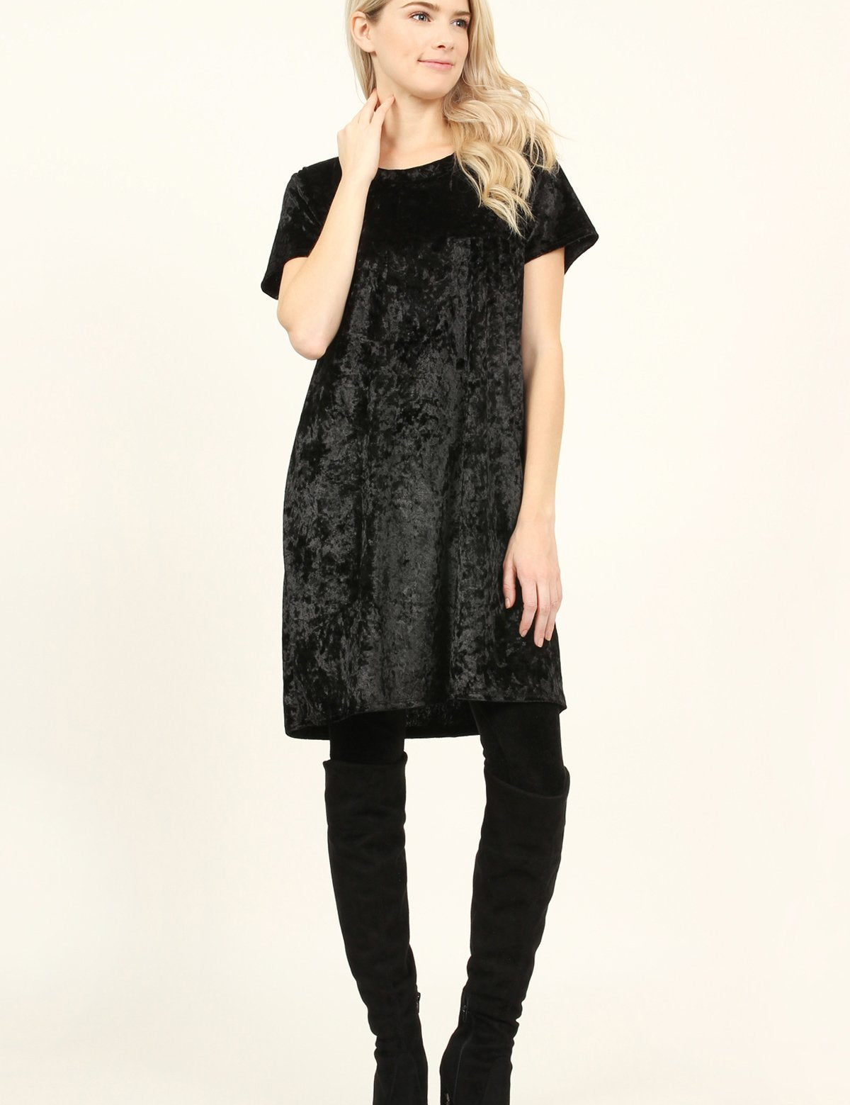 Woman wearing black Calyn Crushed Velvet Tunic Dress with over-the-knee boots, showcasing luxury texture and versatility.