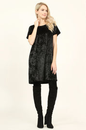 Woman wearing black Calyn Crushed Velvet Tunic Dress with over-the-knee boots, showcasing luxury texture and versatility.