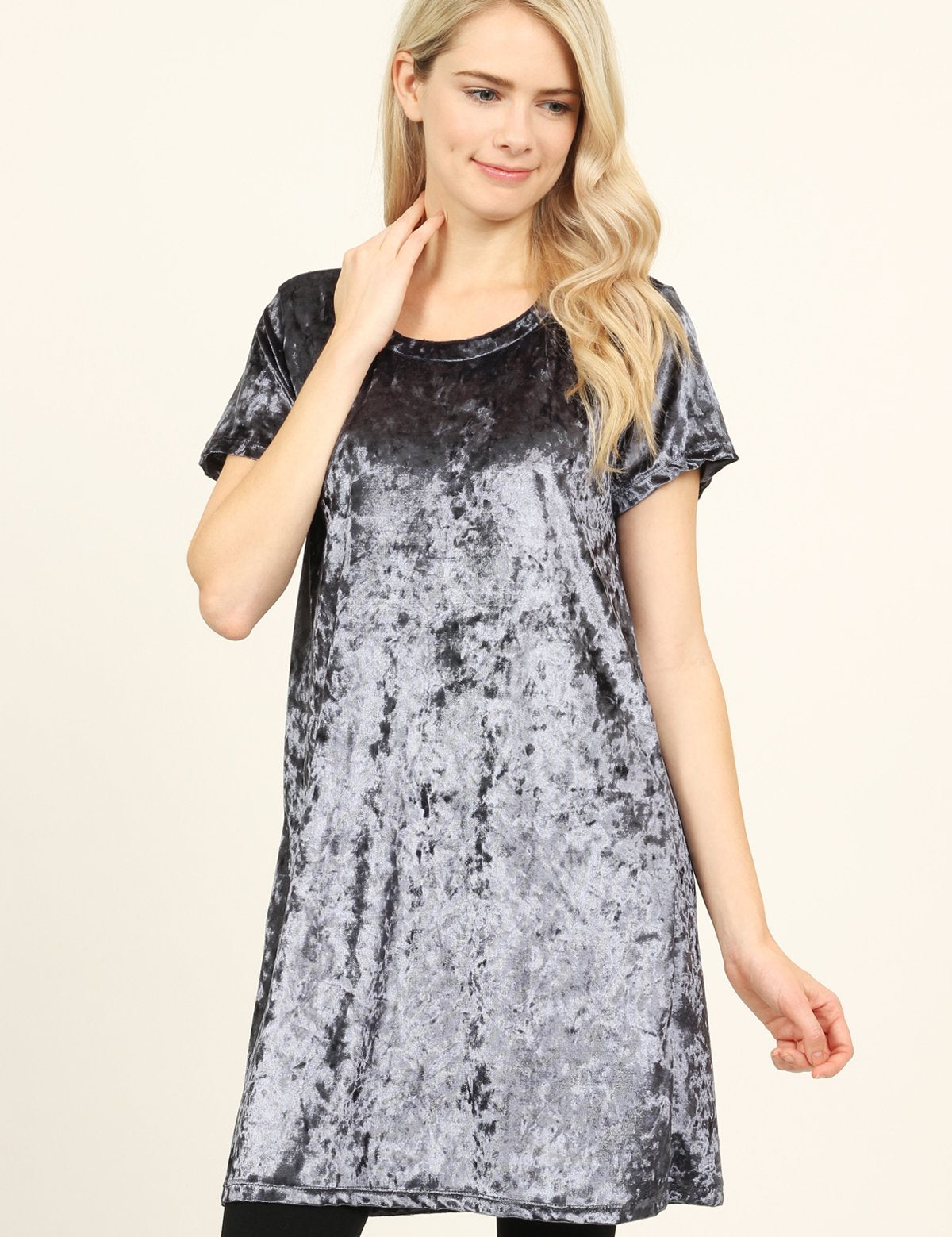 Model wearing Calyn Crushed Velvet Tunic Dress in gray with short sleeves and crew neckline, styled with black leggings.