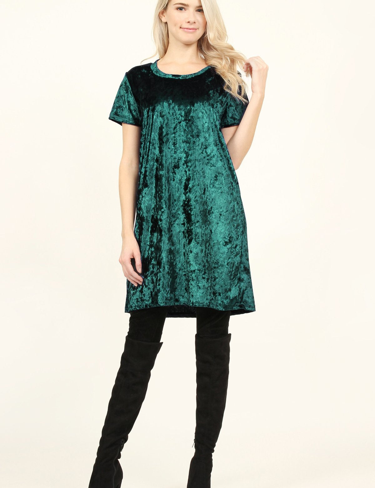 Woman wearing a hunter green Calyn Crushed Velvet Tunic Dress with black over-the-knee boots, showcasing a relaxed and versatile style.