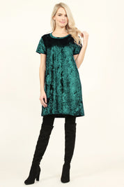 Woman wearing a hunter green Calyn Crushed Velvet Tunic Dress with black over-the-knee boots, showcasing a relaxed and versatile style.