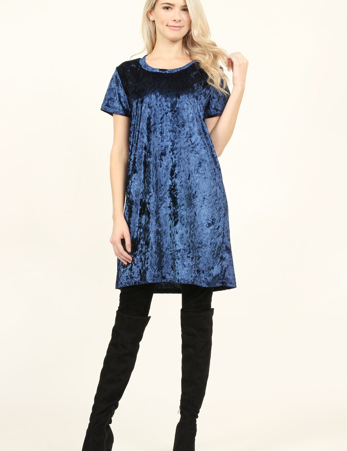 Model wearing a navy Calyn Crushed Velvet Tunic Dress with over-the-knee black boots, showcasing luxurious and versatile style.