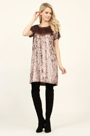 Woman wearing Calyn Crushed Velvet Tunic Dress in rose, styled with black over-the-knee boots, showcasing relaxed fit and luxe texture.