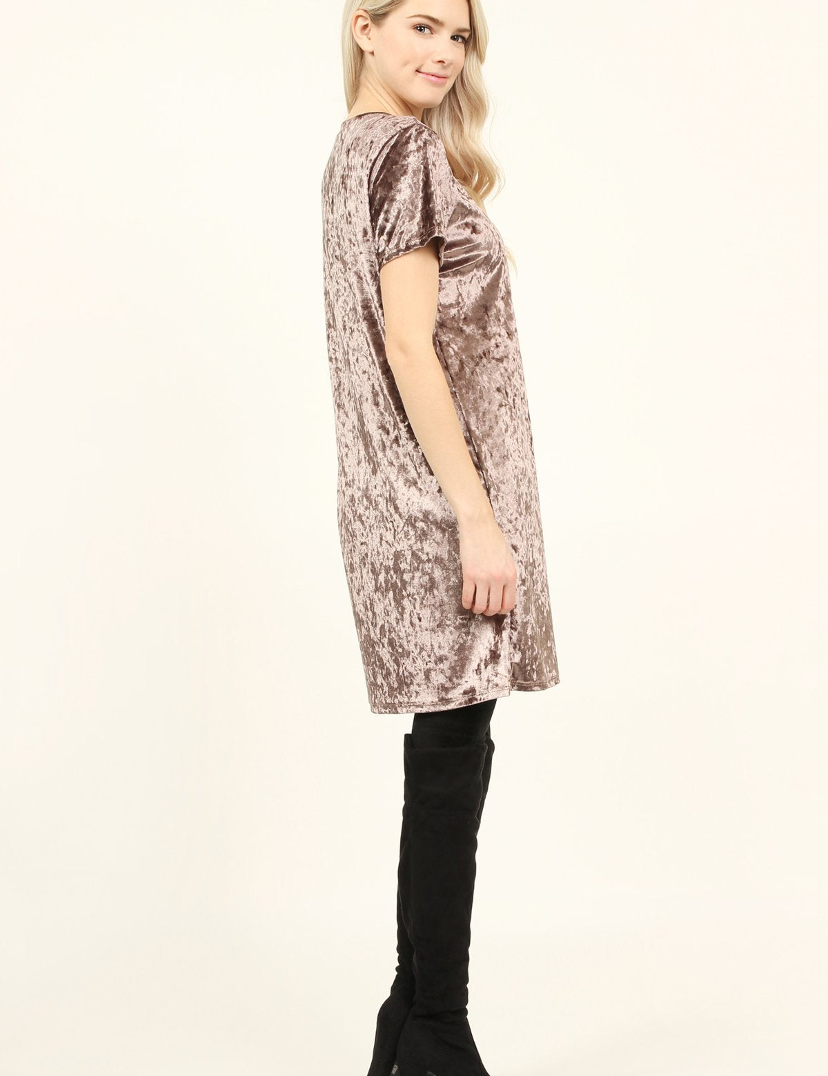 Woman wearing Calyn Crushed Velvet Tunic Dress in taupe with black over-the-knee boots, showcasing luxe texture and relaxed fit.