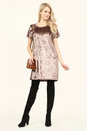 Woman wearing Calyn Crushed Velvet Tunic Dress in rose, paired with over-the-knee black boots and holding a brown leather purse.