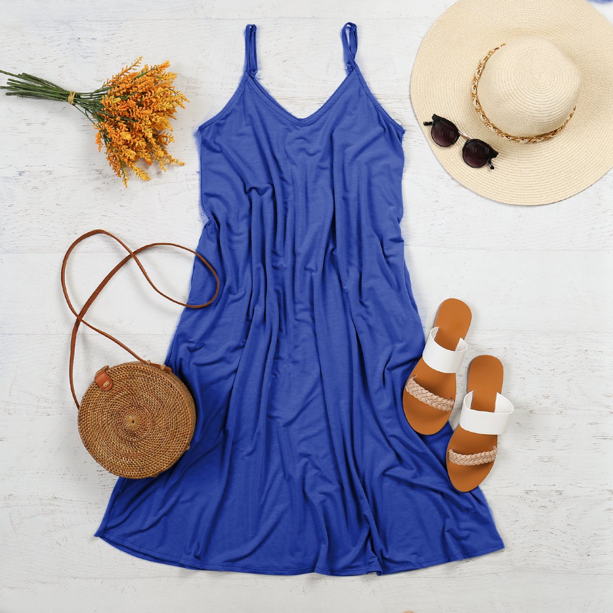 Blue Maribel V-Neck Swing Dress with accessories, including a straw hat, sunglasses, sandals, and a woven bag, styled for spring.