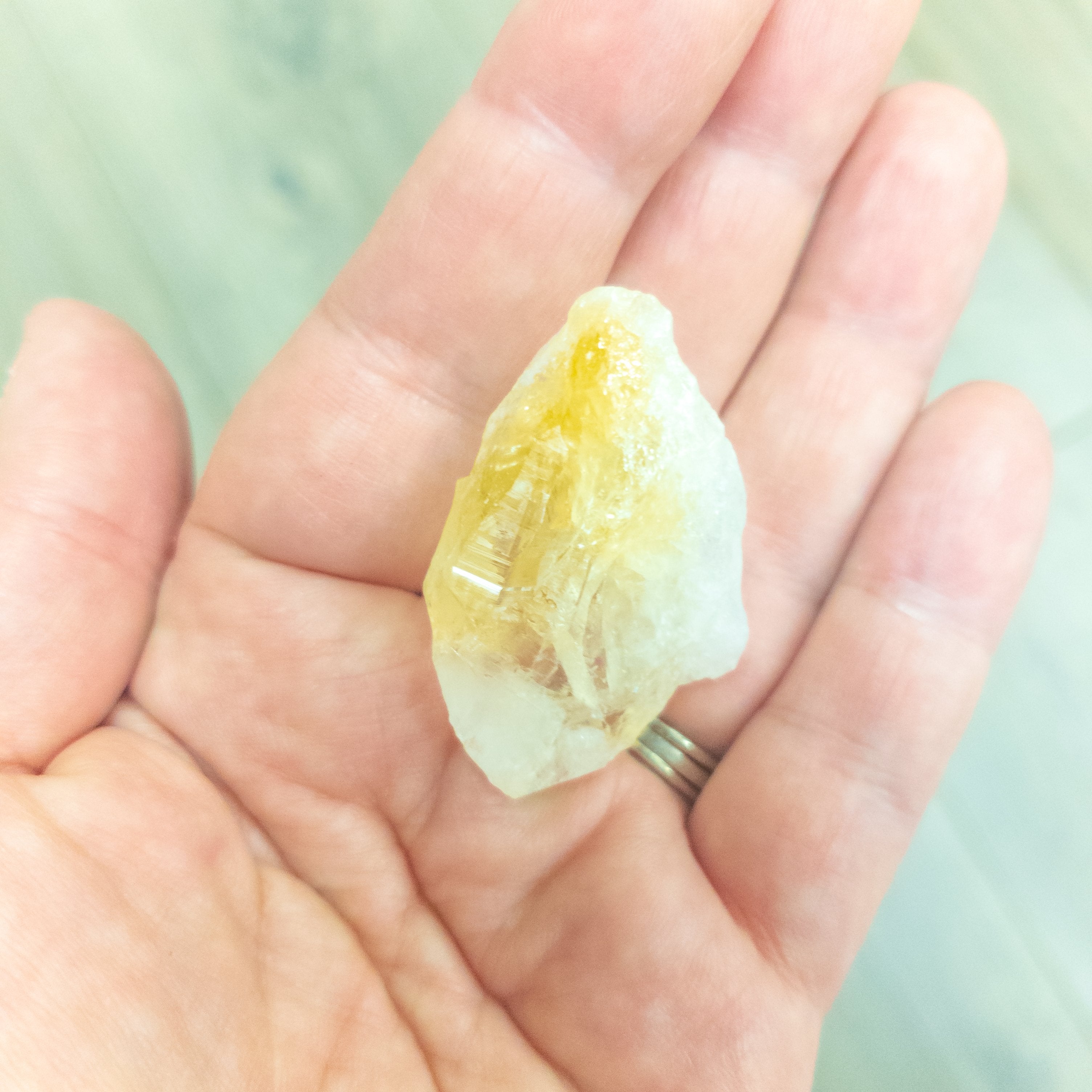 Hand holding a radiant citrine shard crystal, known for attracting positivity and personal power, energized under the super full moon.