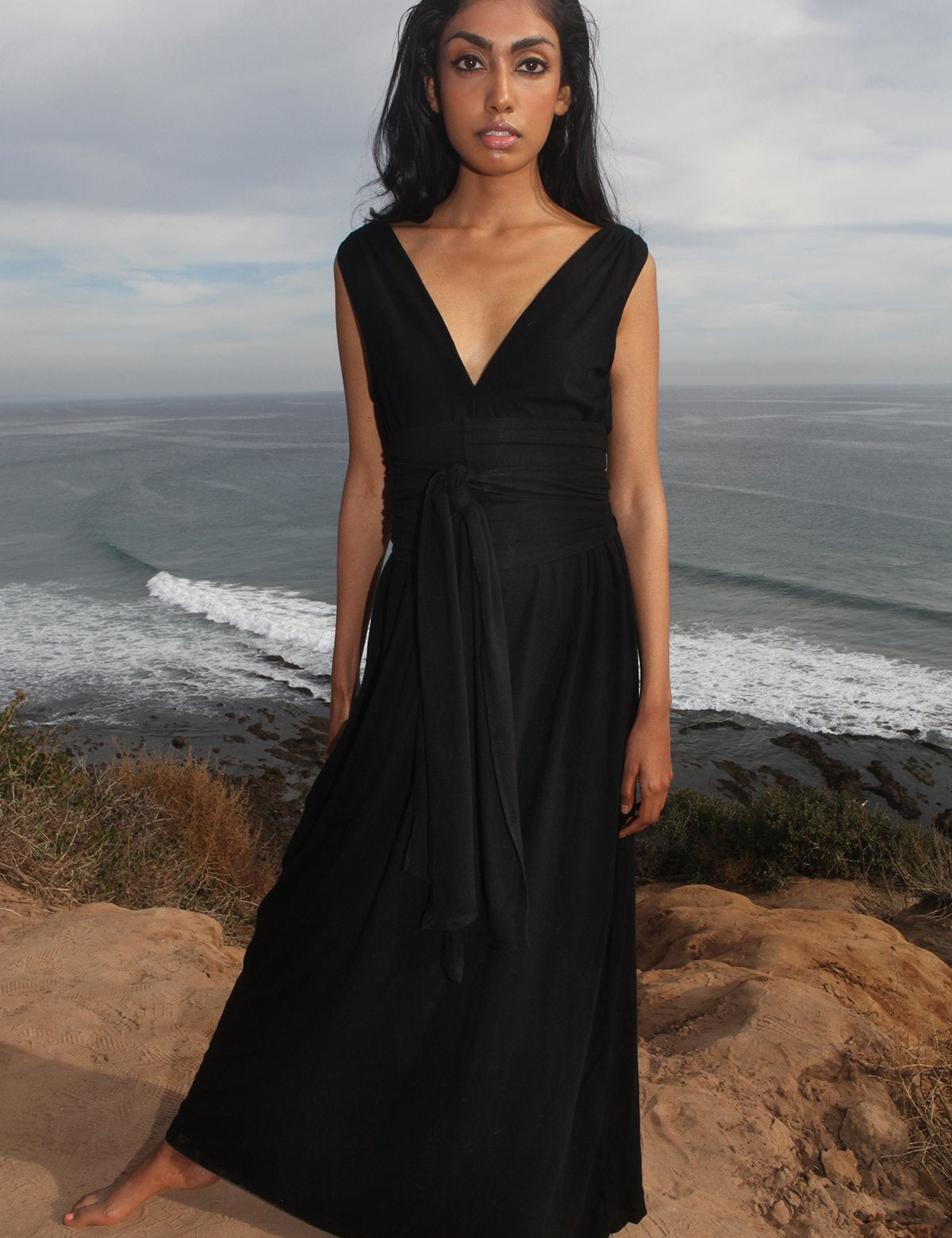Woman wearing Sylvaya Organic Bamboo Maxi Dress with wrap-around belt by the seaside, showcasing a flowing silhouette.