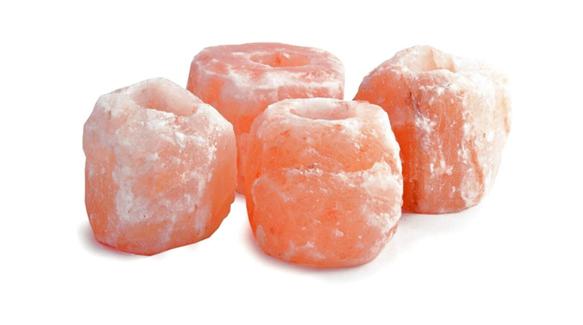 Four handcrafted Himalayan salt candle holders emitting ambient glow, ideal for meditation and relaxation, showcasing unique natural textures.