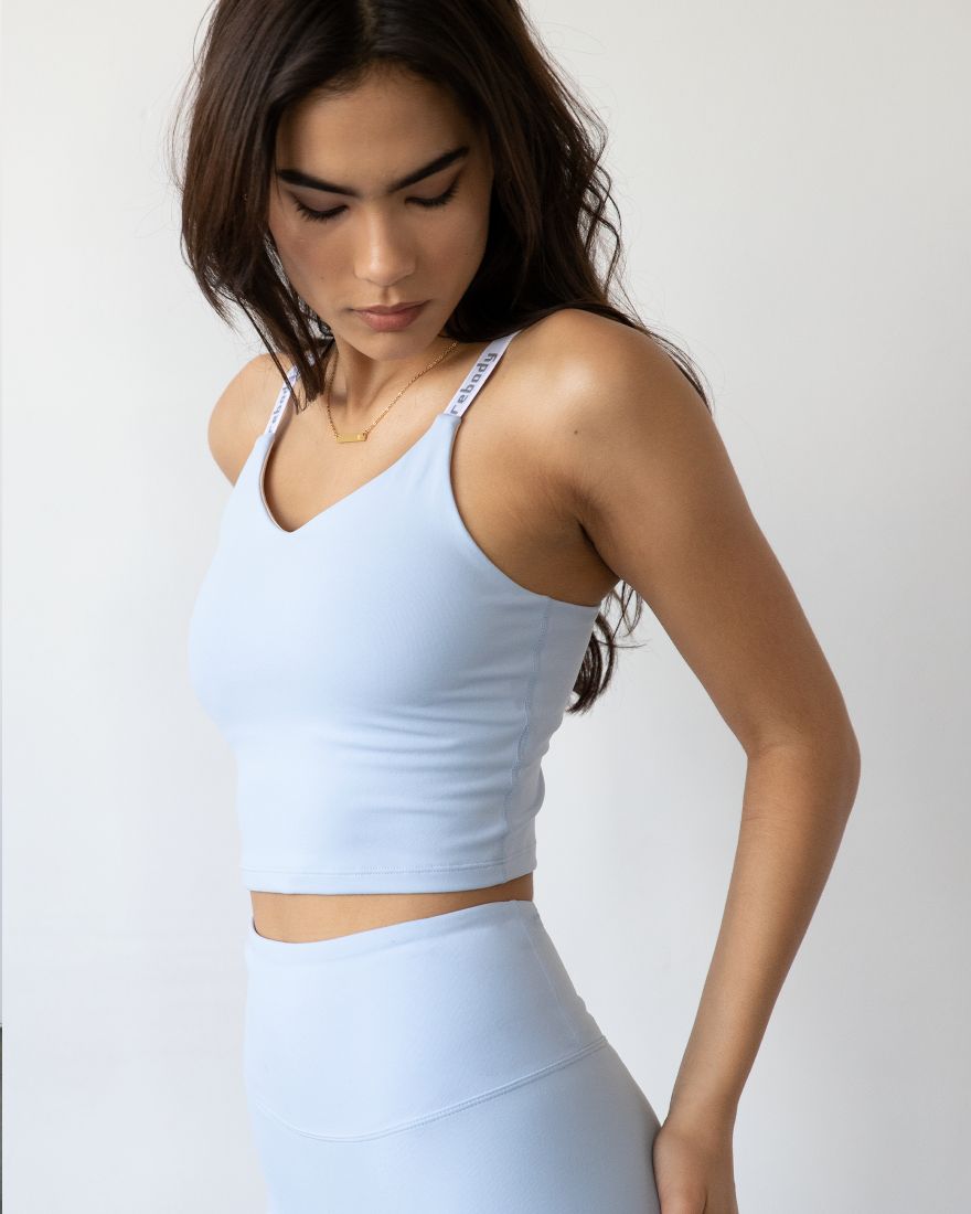 Woman wearing Irynelle Contour Bra Top, soft scoop neckline, light blue color, longline silhouette for yoga and daily elegance.