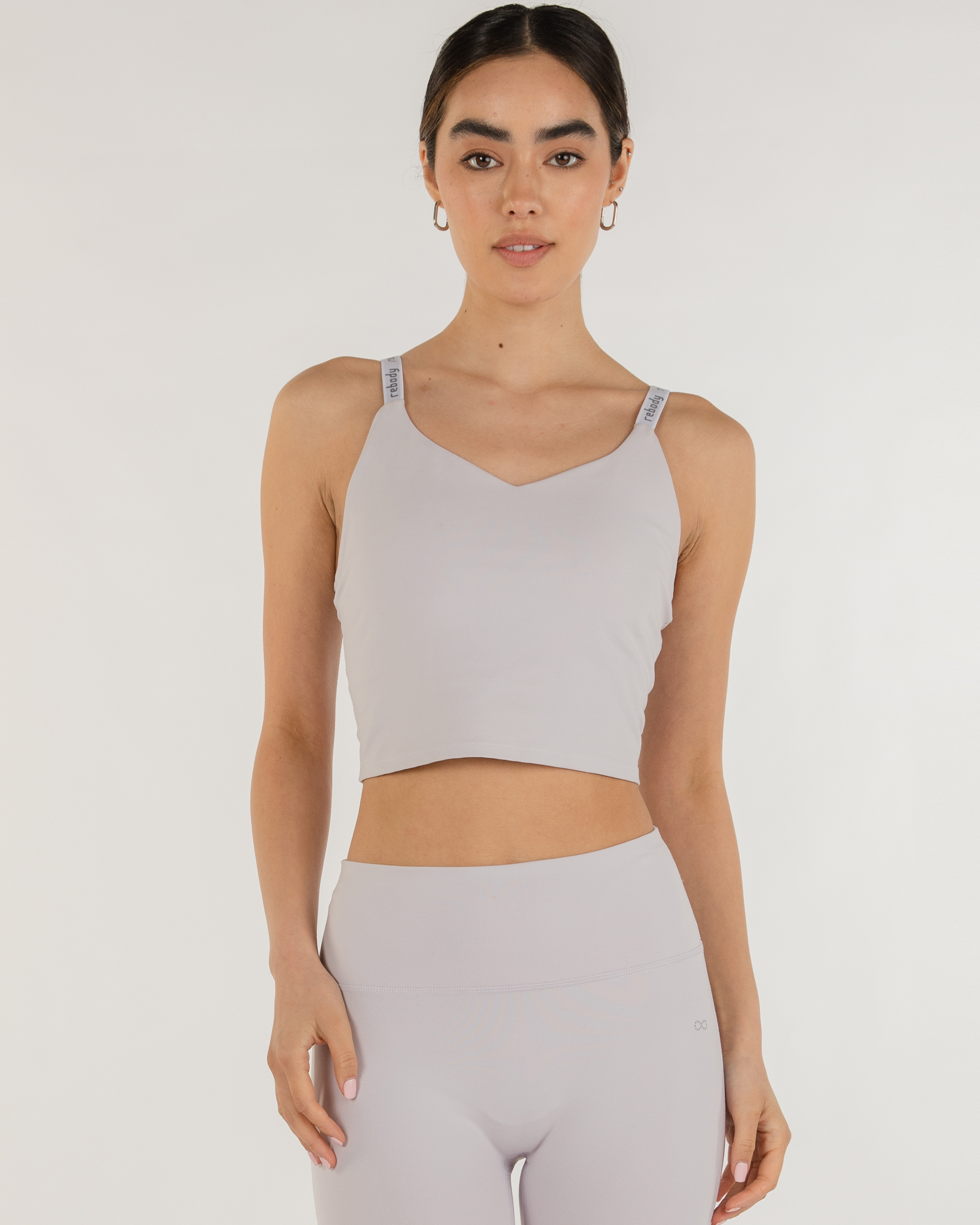 Woman wearing Irynelle Contour Bra Top in soft gray, showcasing its longline silhouette and scoop neckline for yoga or city walks.