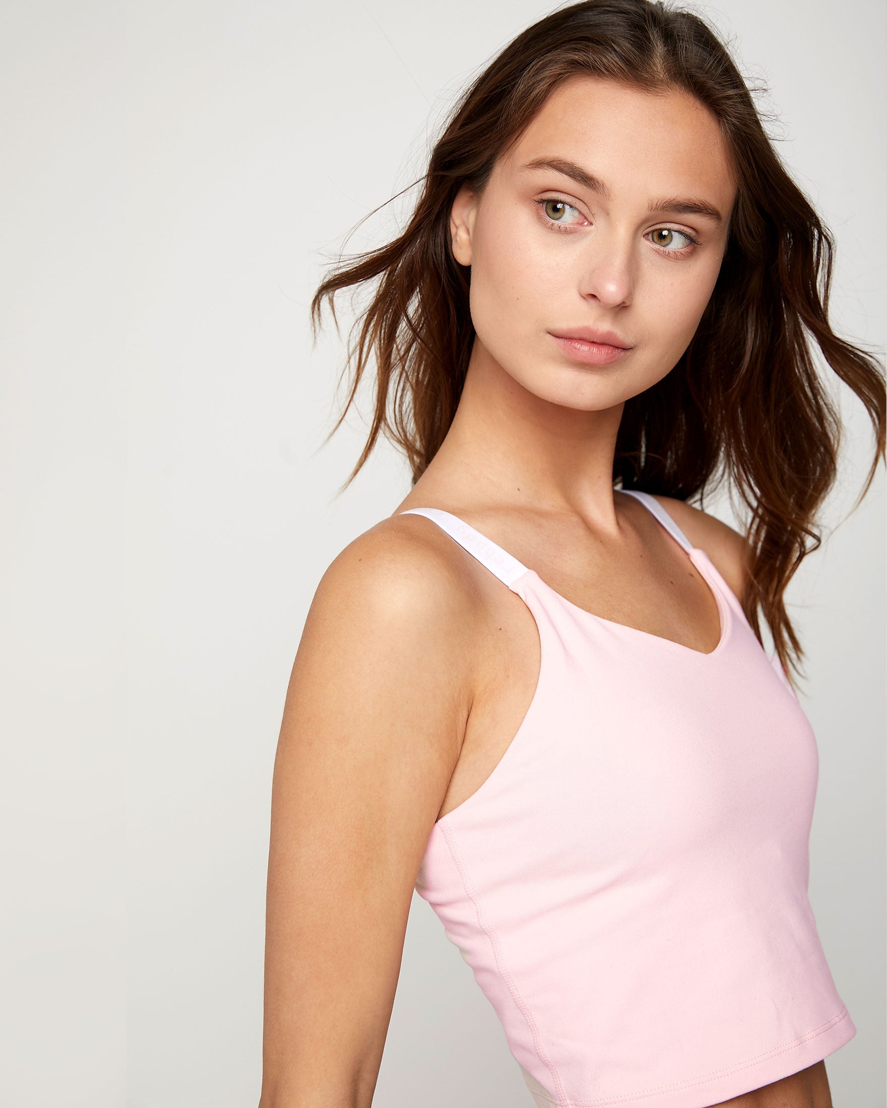 Woman wearing a pink Irynelle Contour Bra Top with a soft scoop neckline, perfect for yoga and everyday elegance, featuring a longline silhouette.