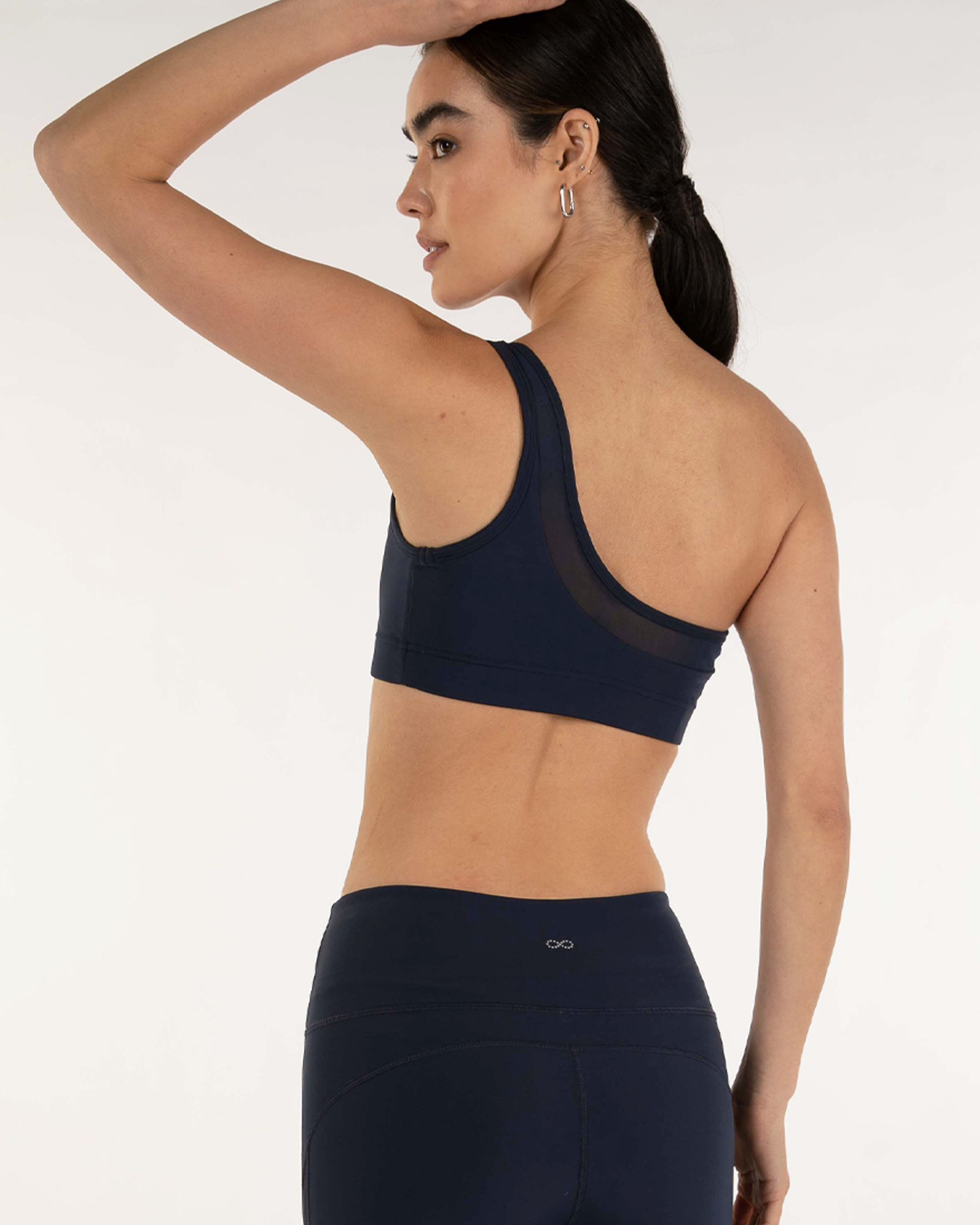 Model wearing Narevia One-Shoulder Mesh Bra showcasing back design and sheer inset, in navy blue for sporty elegance.
