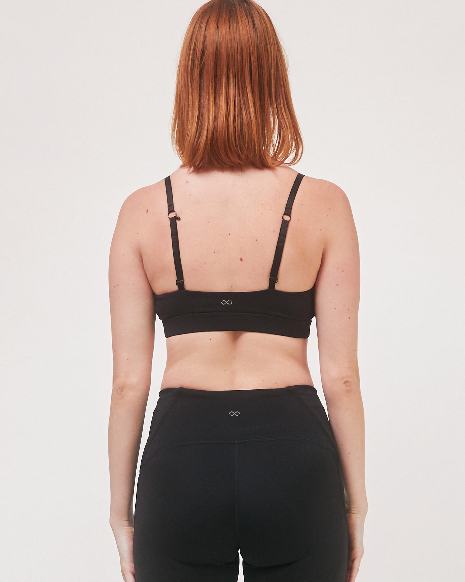Back view of a woman wearing a black Elyrien Cloudlux Bralette with adjustable straps and optional J-hook for added support.