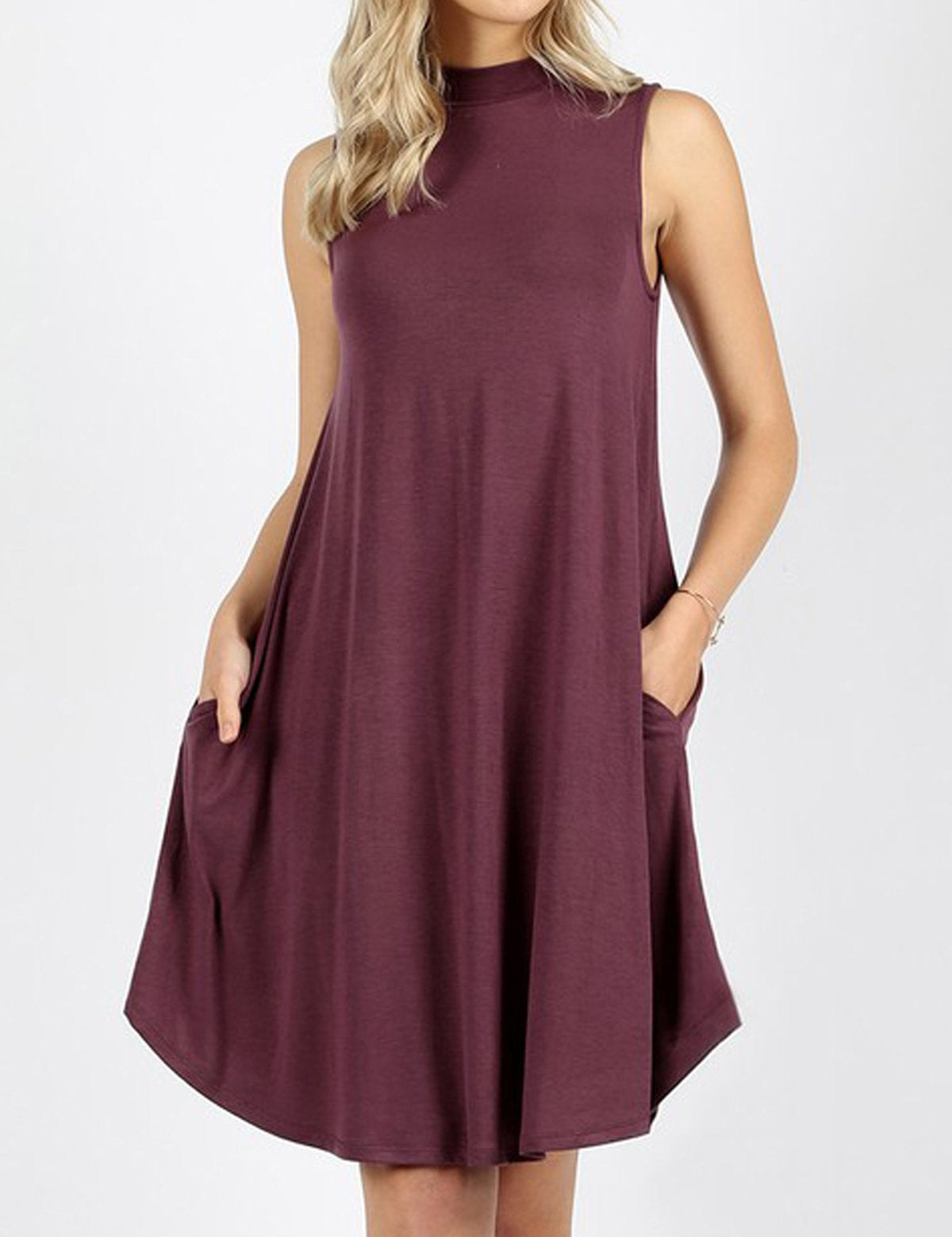 Woman wearing Urban Muse mock neck dress in eggplant color, featuring side pockets and sleeveless design for a modern casual look.