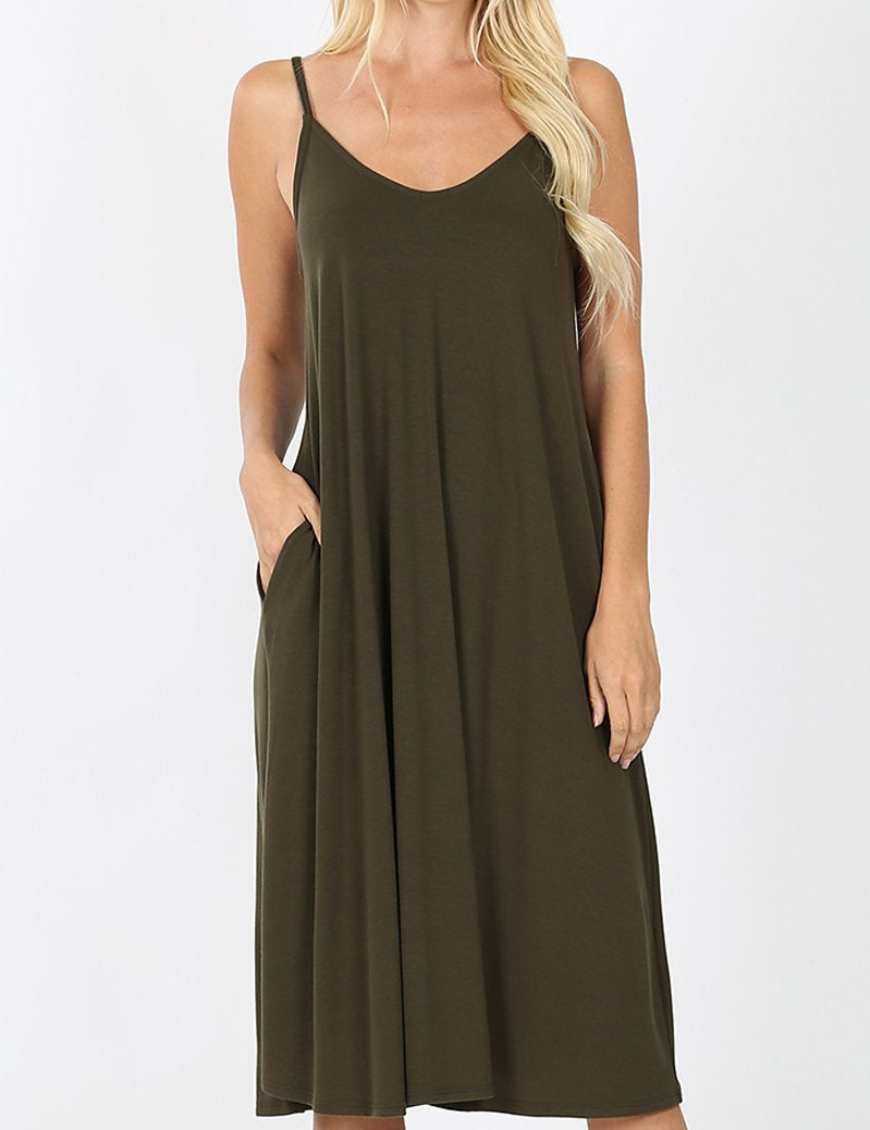 Woman wearing Maribel V-Neck Swing Dress with cami straps, pockets, knee-length hem in olive, showcasing spring style versatility.
