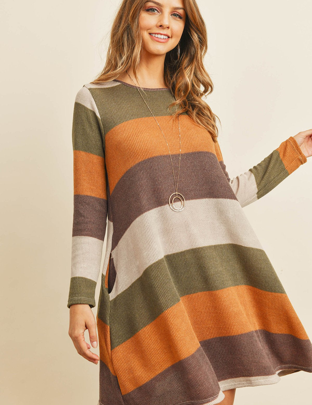 Woman wearing a Solvia Ribbed Swing Pocket Dress with multicolored stripes, featuring long sleeves and round neckline.